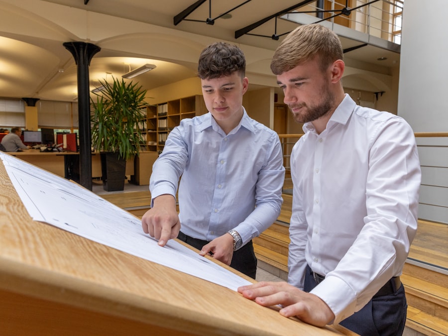 Two engineers reviewing a technical drawing on a table